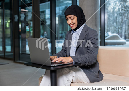 Muslim businesswoman in hijab working on laptop and looking involved Muslim businesswoman in hijab working on laptop and looking involved 130091987