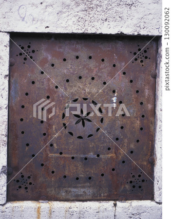Rusty iron plate with a geometric pattern inlaid into the wall of an apartment building in an old street in Rome Rusty iron plate with a geometric pattern inlaid into the wall of an apartment building in an old street in Rome 130092062