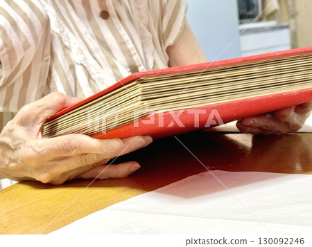 Elderly woman holding a thick photo album 130092246