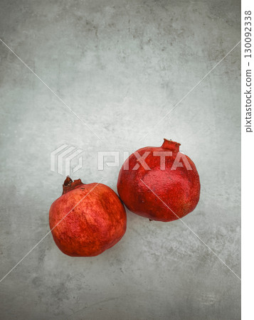 Two pomegranates symbolizing rosh hashanah, love, and rebirth on a textured surface Two pomegranates symbolizing rosh hashanah, love, and rebirth on a textured surface 130092338