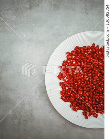 Pomegranate seeds resting on white plate, celebrating rosh hashanah and rebirth Pomegranate seeds resting on white plate, celebrating rosh hashanah and rebirth 130092354