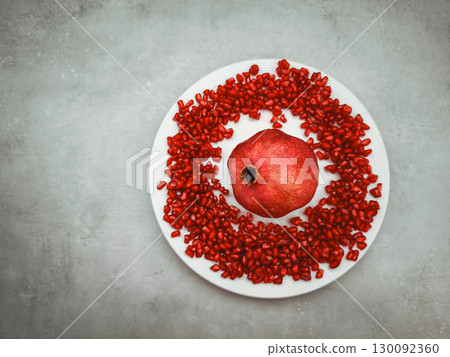 Pomegranate and seeds creating a vibrant rosh hashanah still life on white plate 130092360