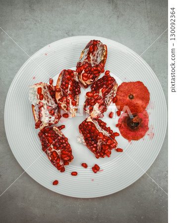 Open pomegranate on white plate symbolizing rosh hashanah and rebirth 130092364