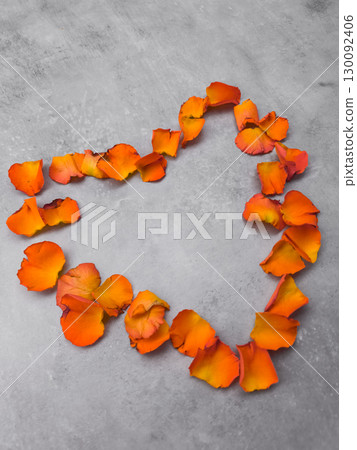 Orange rose petals forming heart shape on gray background 130092406