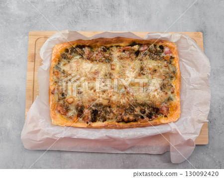 Delicious homemade pizza resting on baking paper and wooden board Delicious homemade pizza resting on baking paper and wooden board 130092420