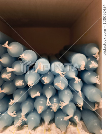 Many light blue paraffin candles with white wicks in a cardboard box 130092484