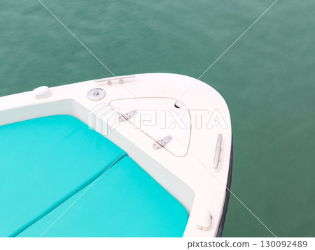 Bow of white motorboat with turquoise cushions floating on calm water 130092489