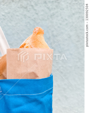 Freshly baked bread in paper bag emerging from blue tote bag in prague Freshly baked bread in paper bag emerging from blue tote bag in prague 130092504