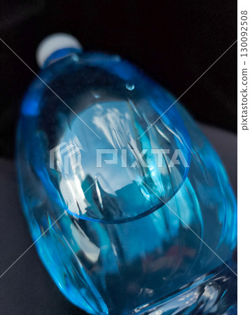 Close up of a blue plastic water bottle reflecting light on dark background Close up of a blue plastic water bottle reflecting light on dark background 130092508