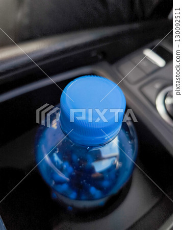 Blue pills inside plastic bottle in car cup holder 130092511