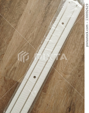 White plastic cable duct for curtains lying on wooden floor in prague 130092629