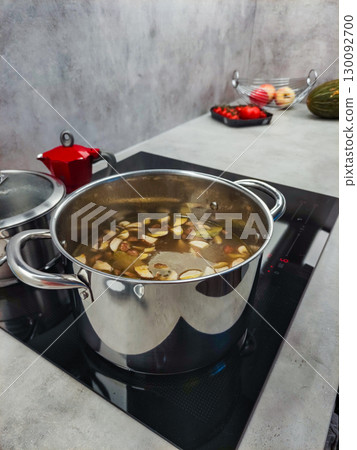 Chef preparing broth with vegetables in stainless steel pot on induction stove Mushroom soup Chef preparing broth with vegetables in stainless steel pot on induction stove Mushroom soup 130092700