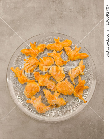 Halloween cookies shaped like bats, pumpkins, and ghosts resting on glass plate, copy space 130092707
