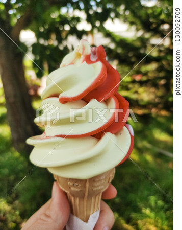 Delicious swirled soft serve ice cream cone enjoyed outdoors mix strawberry and vanilla 130092709
