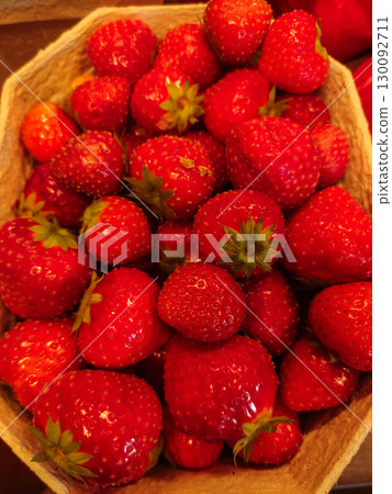 Fresh red strawberries overflowing a cardboard container 130092711