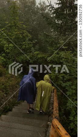 Hikers walking down stairs in rain wearing ponchos in strbske pleso, high tatras mountains 130092736