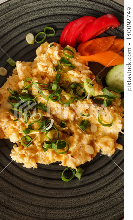 Scrambled eggs with spring onions and vegetables on a dark plate strbske pleso, high tatras Scrambled eggs with spring onions and vegetables on a dark plate strbske pleso, high tatras 130092749