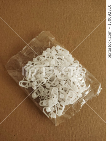 Plastic curtain hooks in transparent bag on brown surface Plastic curtain hooks in transparent bag on brown surface 130092810