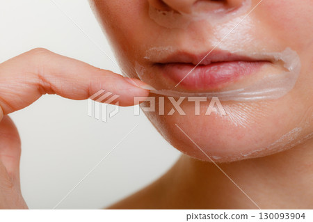 Woman removing facial peel off mask closeup Woman removing facial peel off mask closeup 130093904