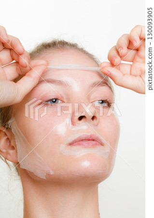 Woman removing facial peel off mask. Woman removing facial peel off mask. 130093905