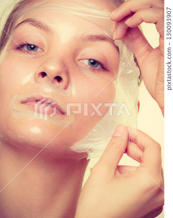 Woman removing facial peel off mask. Woman removing facial peel off mask. 130093907