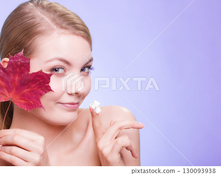 Skin care. Face of young woman girl with red maple leaf. Skin care. Face of young woman girl with red maple leaf. 130093938