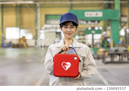 Female worker with AED at factory Female worker with AED at factory 130095537