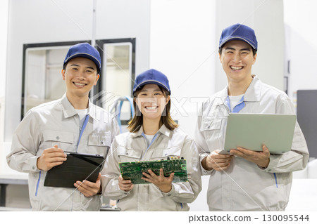 Male and female workers inspecting products using gadgets in factory Male and female workers inspecting products using gadgets in factory 130095544