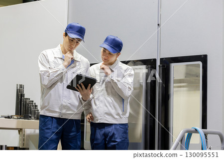 A group of workers inspecting a machine using a tablet PC 130095551