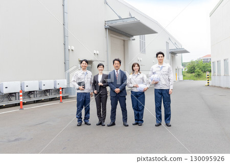 A group of company employees lined up in front of a building 130095926