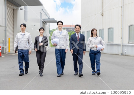 A group of workers walking in front of a factory A group of workers walking in front of a factory 130095930
