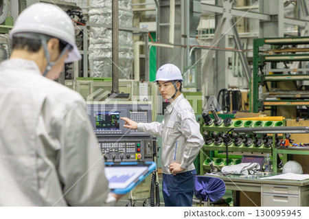 A worker operating a machine on a factory control panel 130095945