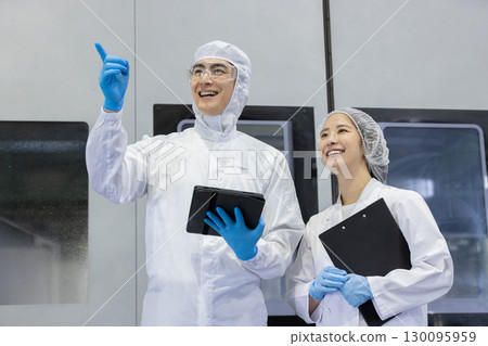 工廠裡穿著防護衣的工人使用平板電腦 130095959