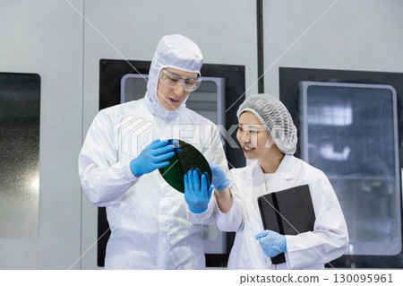 工廠裡穿著防護衣的工人使用平板電腦 130095961