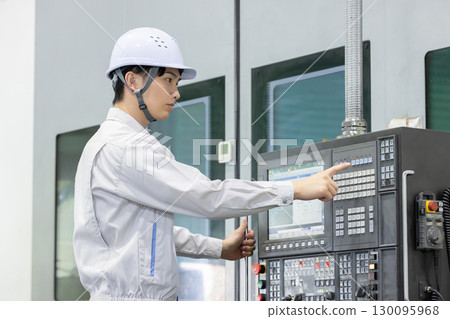 Male worker working in front of a factory control panel 130095968