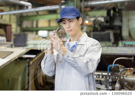 一名男工人在工廠檢查車床加工和銑削的產品 一名男工人在工廠檢查車床加工和銑削的產品 130096020
