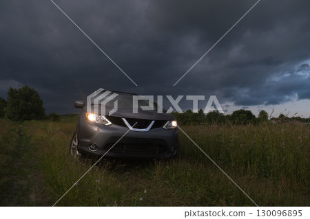 SUV in a Field Under Dramatic Skies 130096895