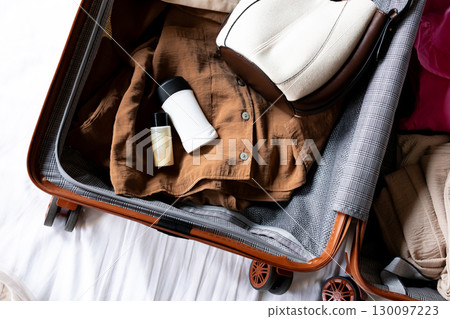Packed suitcase with clothing, toiletries, and hat ready for travel or vacation Packed suitcase with clothing, toiletries, and hat ready for travel or vacation 130097223