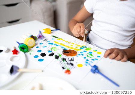 Child painting colorful abstract art with sponges using yellow, blue, green, and black dots Child painting colorful abstract art with sponges using yellow, blue, green, and black dots 130097230