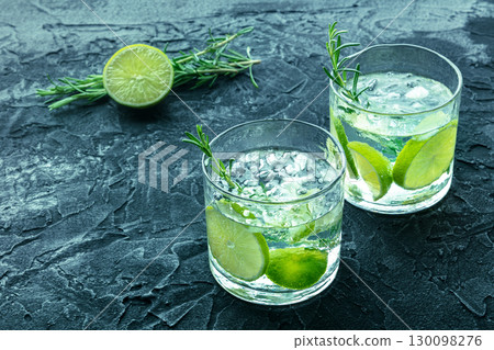 Gin tonic, two glasses of gin with soda, lime, rosemary, and plenty of ice 130098276