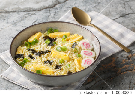Delicious saimin soup with wheat egg noodles, seaweed, green onion, omelet and fish cake close-up in a plate. Horizontal 130098826