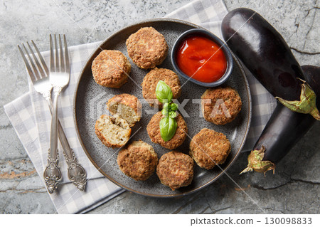 Delicious fried eggplant fritters served with tomato sauce close-up in a plate. Horizontal top view 130098833