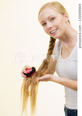Blonde girl with long braid hair holds brush Blonde girl with long braid hair holds brush 130099004