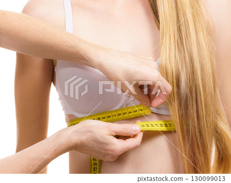Woman measuring girl under breast 130099013