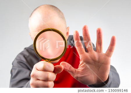 man hides his face with a magnifying glass. man hides his face with a magnifying glass. 130099146