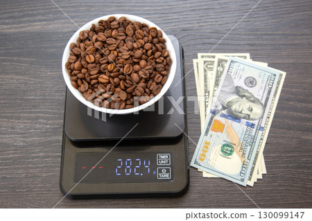 A white bowl filled with roasted coffee beans sits on a digital scale  130099147
