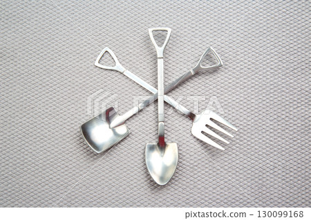decorative fork and spoons in the form of spades on a gray background. food tools. decorative fork and spoons in the form of spades on a gray background. food tools. 130099168
