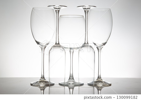 A minimalist display of five empty wine glasses with slender stems 130099182