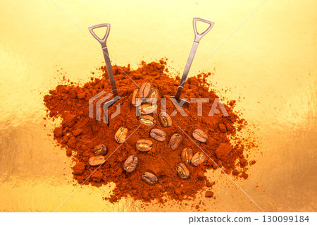 Close-up of two shovels in a pile of rich ground coffee, surrounded by whole coffee beans 130099184