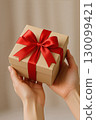 Hand holding gift box with red ribbon 130099421